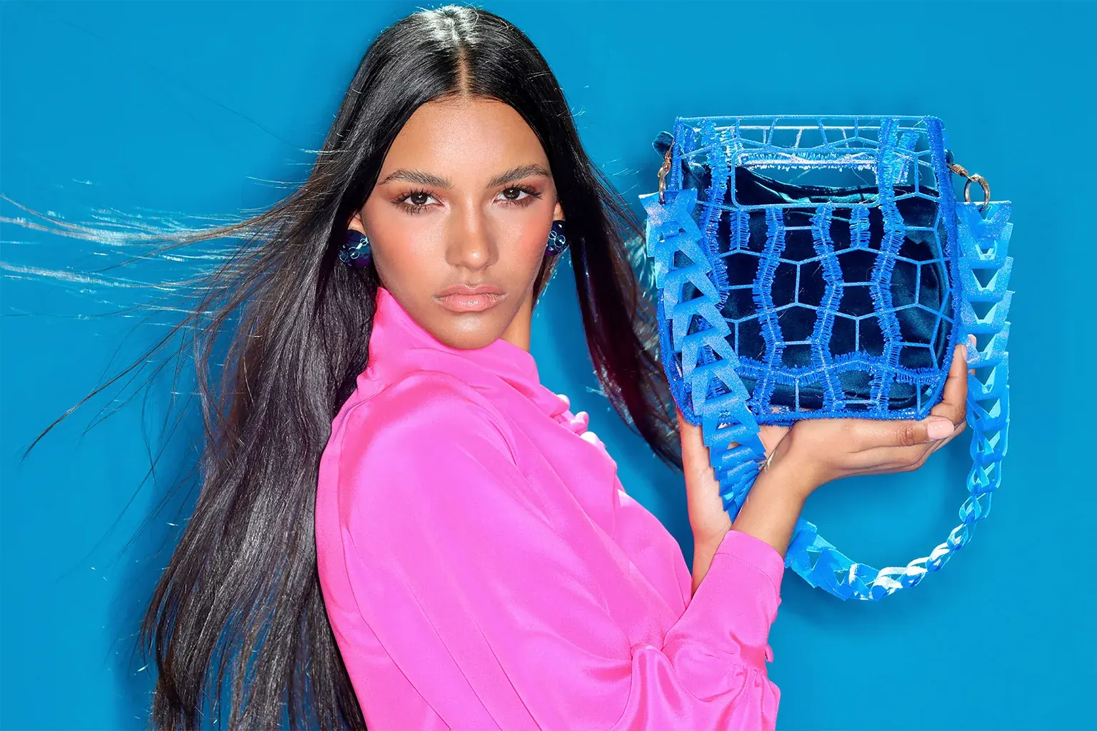 Model in vivid pink holding a blue 3D printed bag