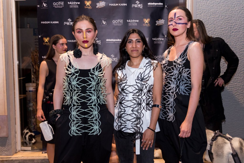La diseñadora de Nodos by G, Gelareh H.Karimi, llevando un chaleco impreso en 3D de su propia marca, una camisa de la nueva temporada de Masum Karimi y posando con sus dos modelos de la pasarela del evento street runway atenas