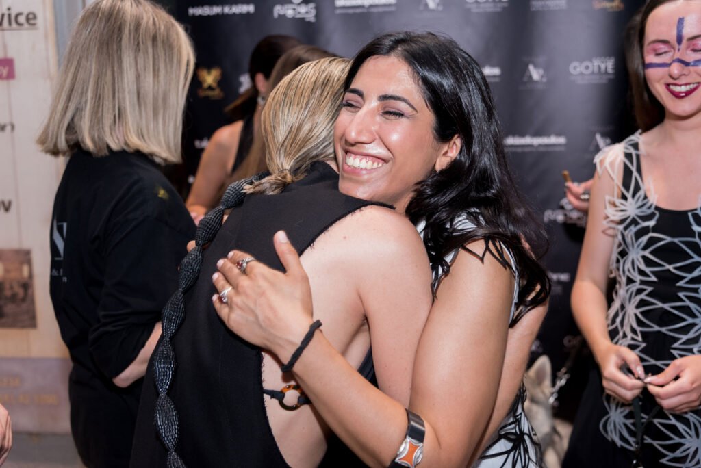 La diseñadora de Nodos by G, Gelareh H.Karimi, llevando un chaleco impreso en 3D de su propia marca, una camisa de la nueva temporada de Masum Karimi y posando con sus dos modelos de la pasarela del evento street runway atenas